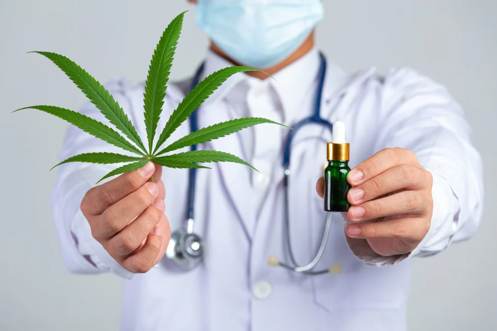 medical doctor holding cannabis leaf-bottle cannabis oil white wall for cannabiz elite